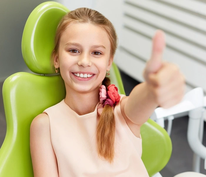 Girl giving a thumbs up in dentist's chair